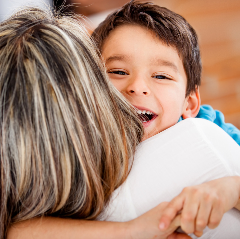 Happy boy hugging his mother and smiling