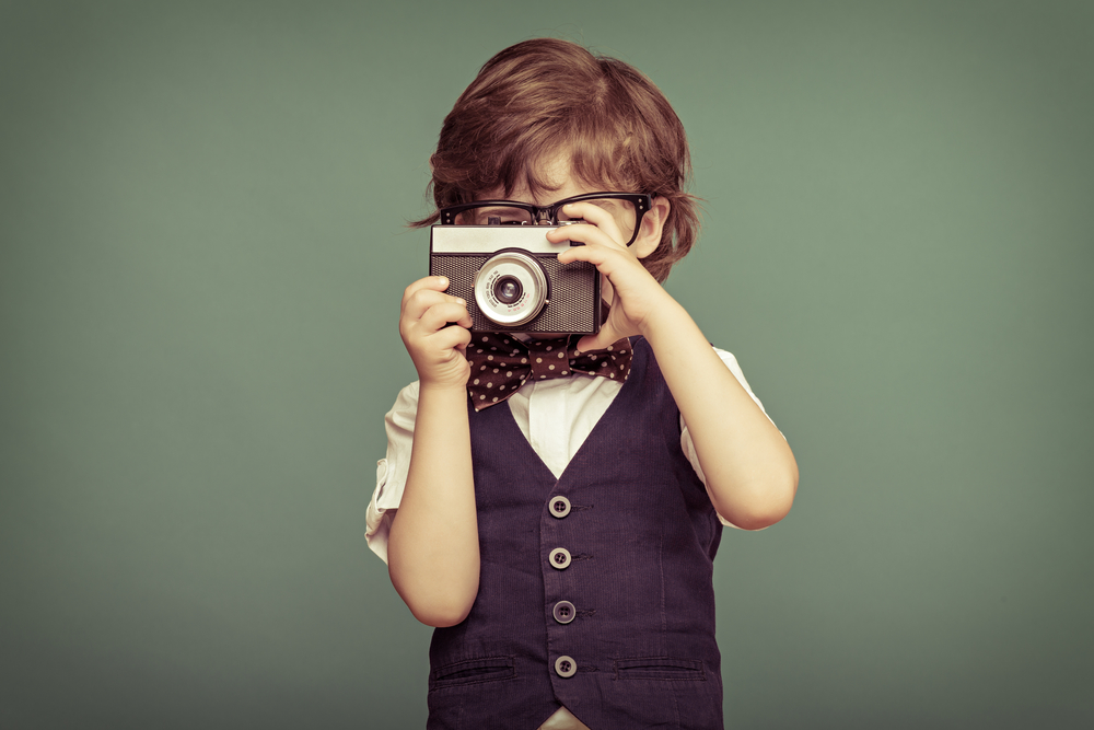 Cheerful smiling child (boy) holding a instant camera