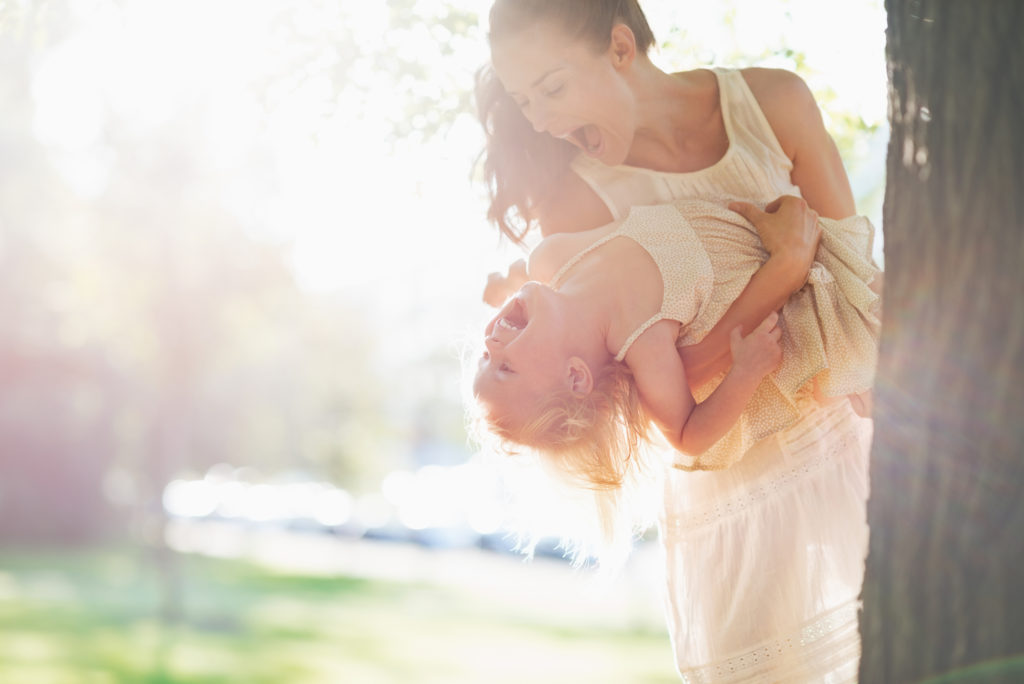 Happy mother and baby having fun near tree